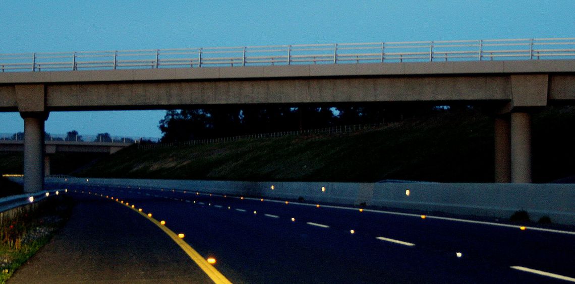 Photo of a motorway at night, with Catseyes reflecting the light of headlamps back at the vehicle it is coming from