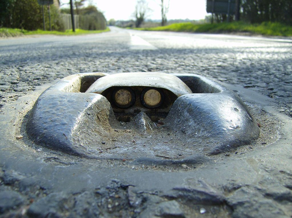 Photo of a Catseye set into a road, with the rubber housing and the glass reflectors visible