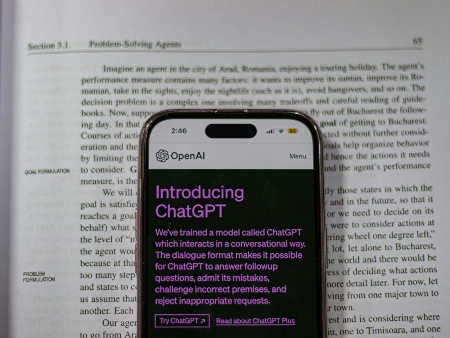 A smartphone displaying OpenAI's ChatGPT. A smartphone on top of a book on problem-solving agents, the phone displays OpenAI's ChatGPT.